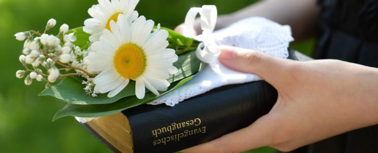 Konfirmandin mit Gesangbuch Konfirmandin mit Gesangbuch und Blumen.